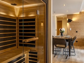 Ein modernes Interieur mit einer Holzsauna, einem Essbereich mit Tisch für zwei Personen und einer Holzwand.