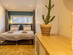 A bedroom with a bed, a window, a potted plant, and a wooden bedside table. - Convenient apartment in Plagne 1800 - 6 guests (La Plagne 1800)