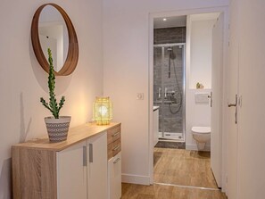 Ein modernes Badezimmer mit Dusche, Toilette und Waschtisch inklusive Spiegel und Topfpflanze.
