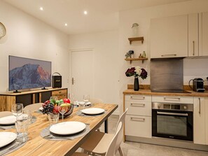A modern kitchen with a built-in oven, a coffee machine, and a wooden dining table set for four. - Convenient apartment in Plagne 1800 - 6 guests (La Plagne 1800)