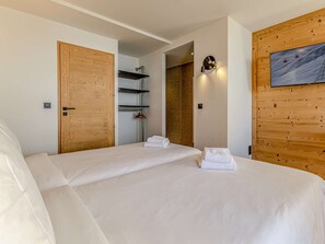 Ein Hotelzimmer mit einem großen Bett, Holztüren, einem Kleiderständer und einem Bild an der Wand.