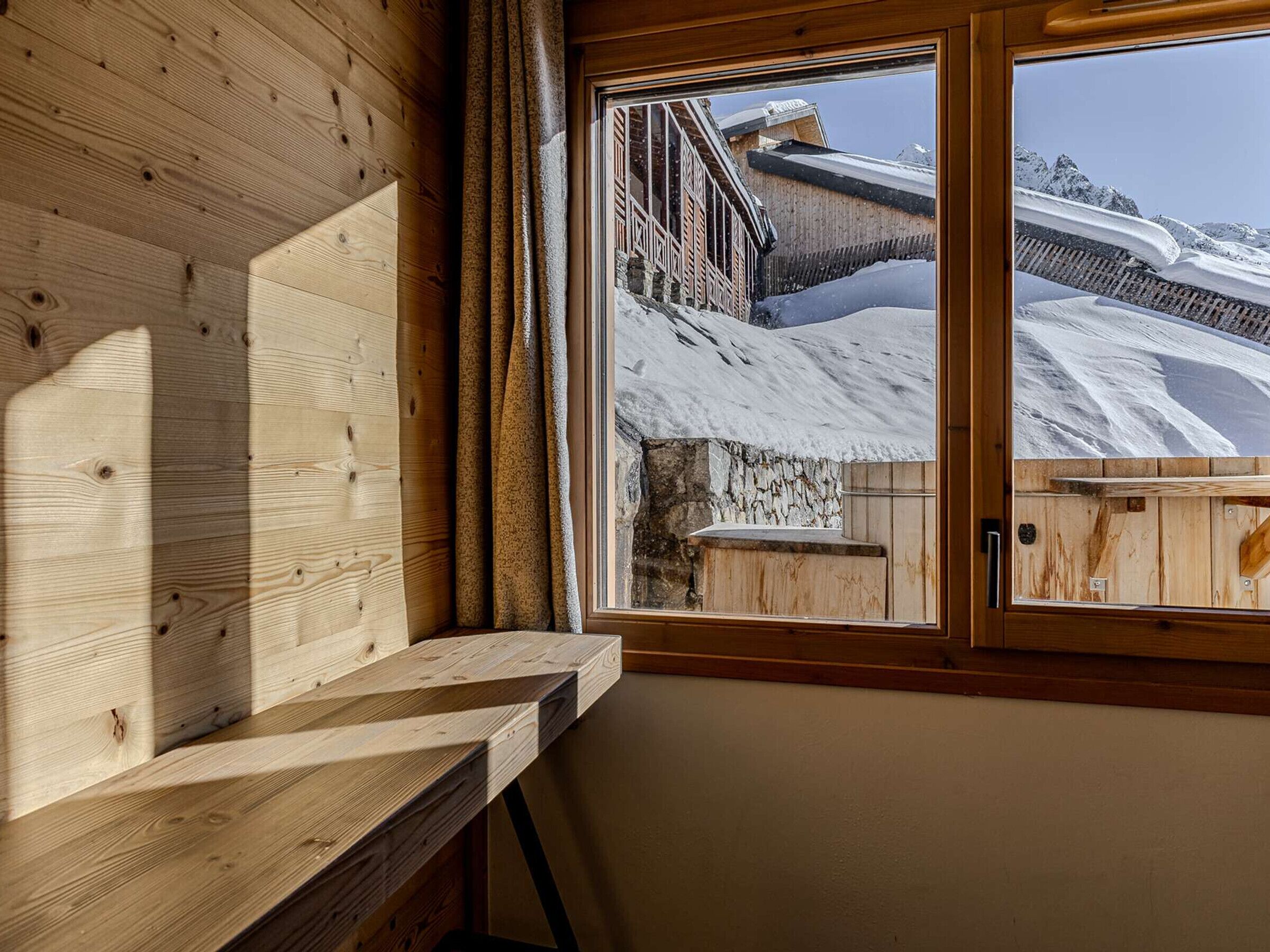 Un intérieur en bois avec une fenêtre donnant sur un paysage enneigé.