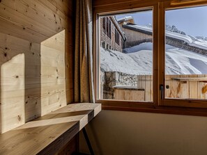 A wooden interior with a window overlooking a snowy outdoor scene. - Modern apartment in Belle Plagne - 6 guests (Belle Plagne)