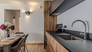 Moderni keittiö, jossa on musta työtaso, ruostumattomasta teräksestä valmistettu pesuallas ja sisäänrakennettu liesituuletin.