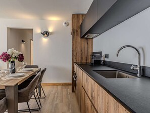 Eine moderne Küche mit schwarzem Arbeitsplatz, Edelstahl-Spüle und integrierter Dunstabzugshaube.