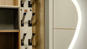 Ein Zimmer mit einem Holzboden, einer weißen Wand mit einer runden Lampe und einer Tür mit Griff.