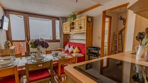 Et hyggeligt spiseområde med træmøbler, en rød sofa og en køkkenø.