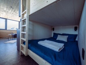 A bunk bed with a blue mattress and white bedding, a wooden ladder, and a small table with a chair. - Stunning apartment, panoramic view - 6 guests (Plagne Aime 2000)