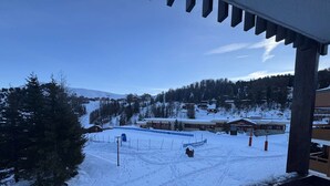 Een bergresort in de sneeuw met chalets, een skilift en een heldere lucht.