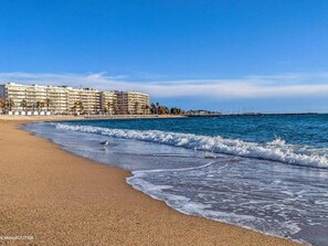 Ein Strand mit einem Hotel im Hintergrund.