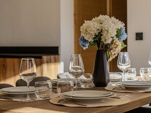 A dining table set with plates, glasses, and a vase of flowers. - Spacious apartment - 8-10 guests. Mountain view (Belle Plagne)