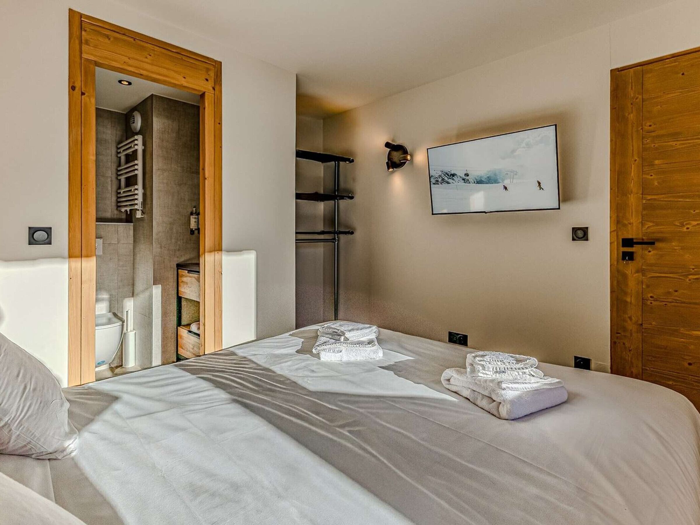 Une chambre à coucher avec un lit, une porte en bois, une douche et un tableau encadré au mur.