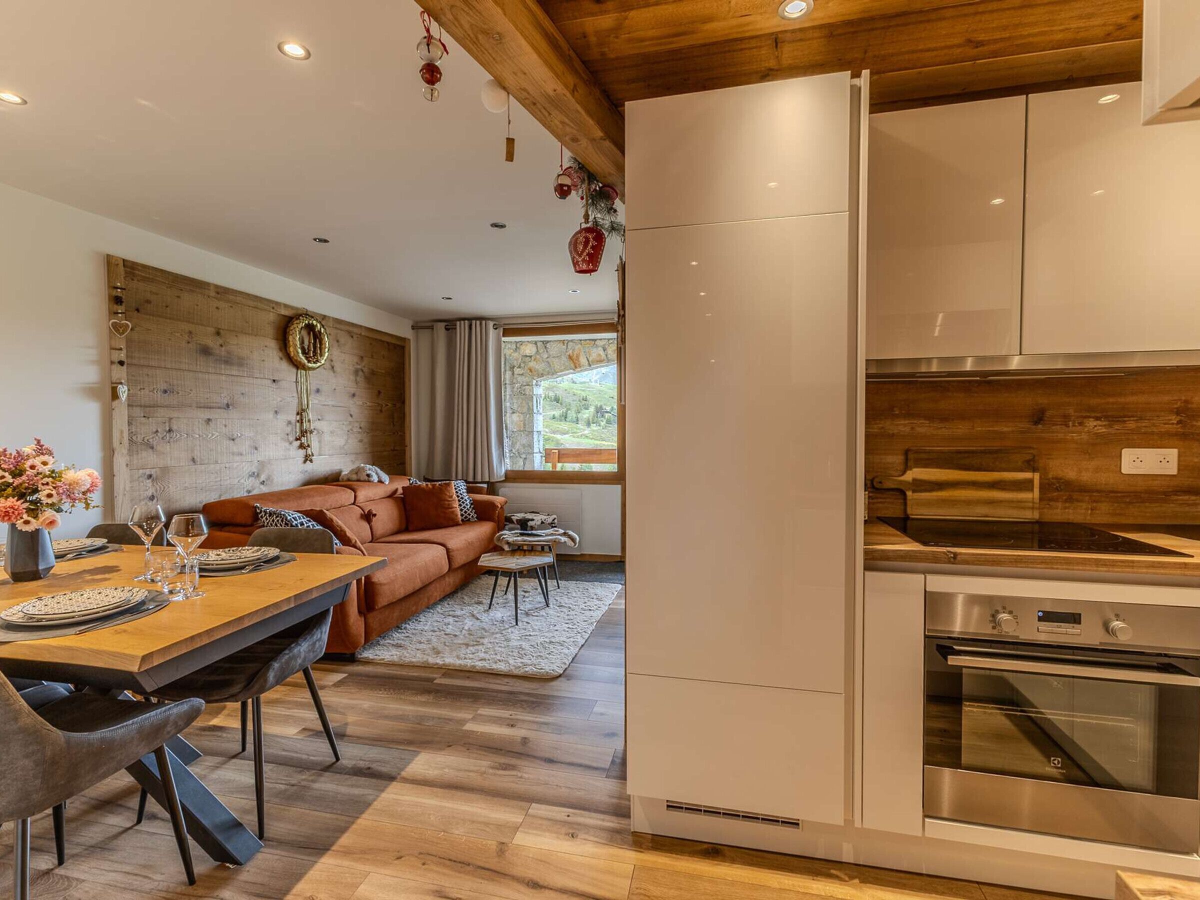 Une cuisine moderne avec des appareils en acier inoxydable, un plafond en bois et un mur en pierre.