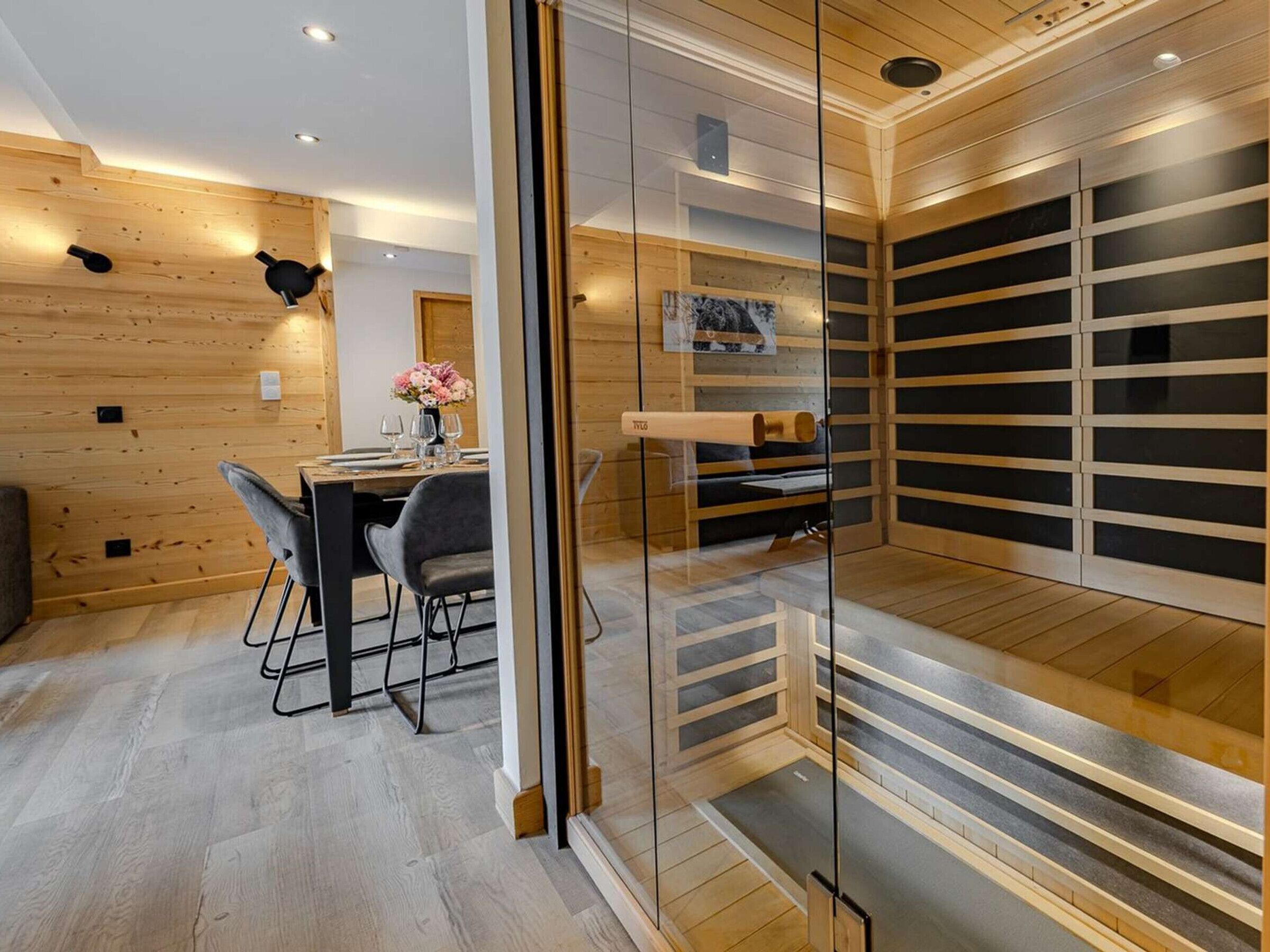 A modern interior with a dining area, a glass partition, and a sauna.