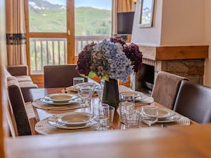 A dining table set for six with plates, glasses, and a vase of flowers. - Comfortable apartment - 8 guests - Belle Plagne (Belle Plagne)