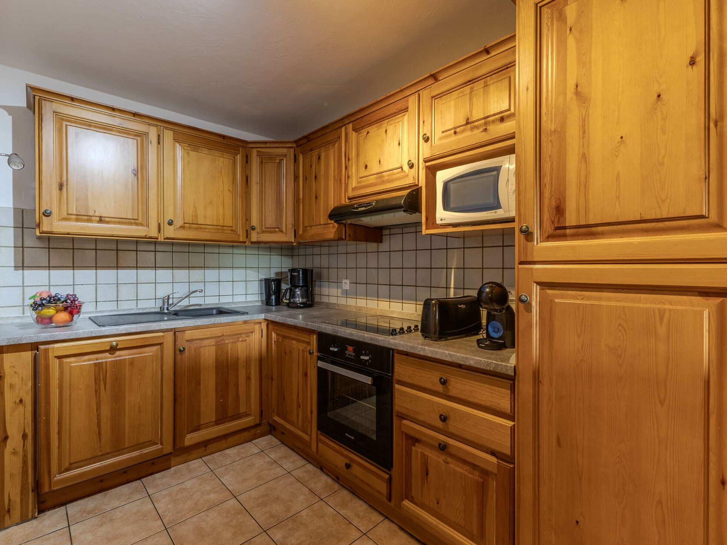 A kitchen with wooden cabinets, a microwave, a toaster, and a coffee maker.