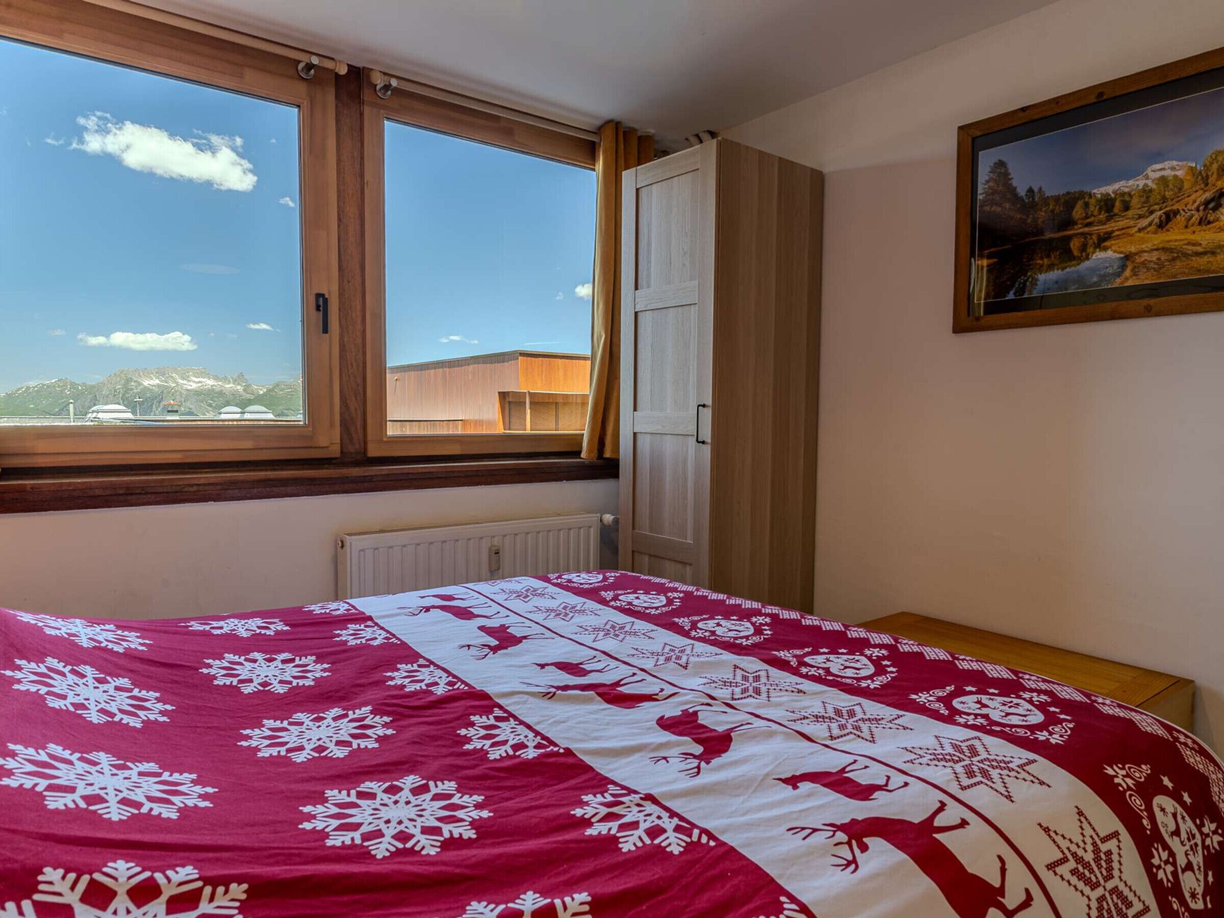 Una camera da letto con un letto, una finestra, un termosifone, un armadio e un quadro appeso al muro.
