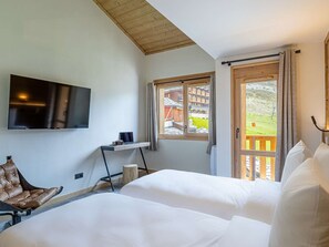 Ein Schlafzimmer mit Fernseher, Schreibtisch, Stuhl und Bett.