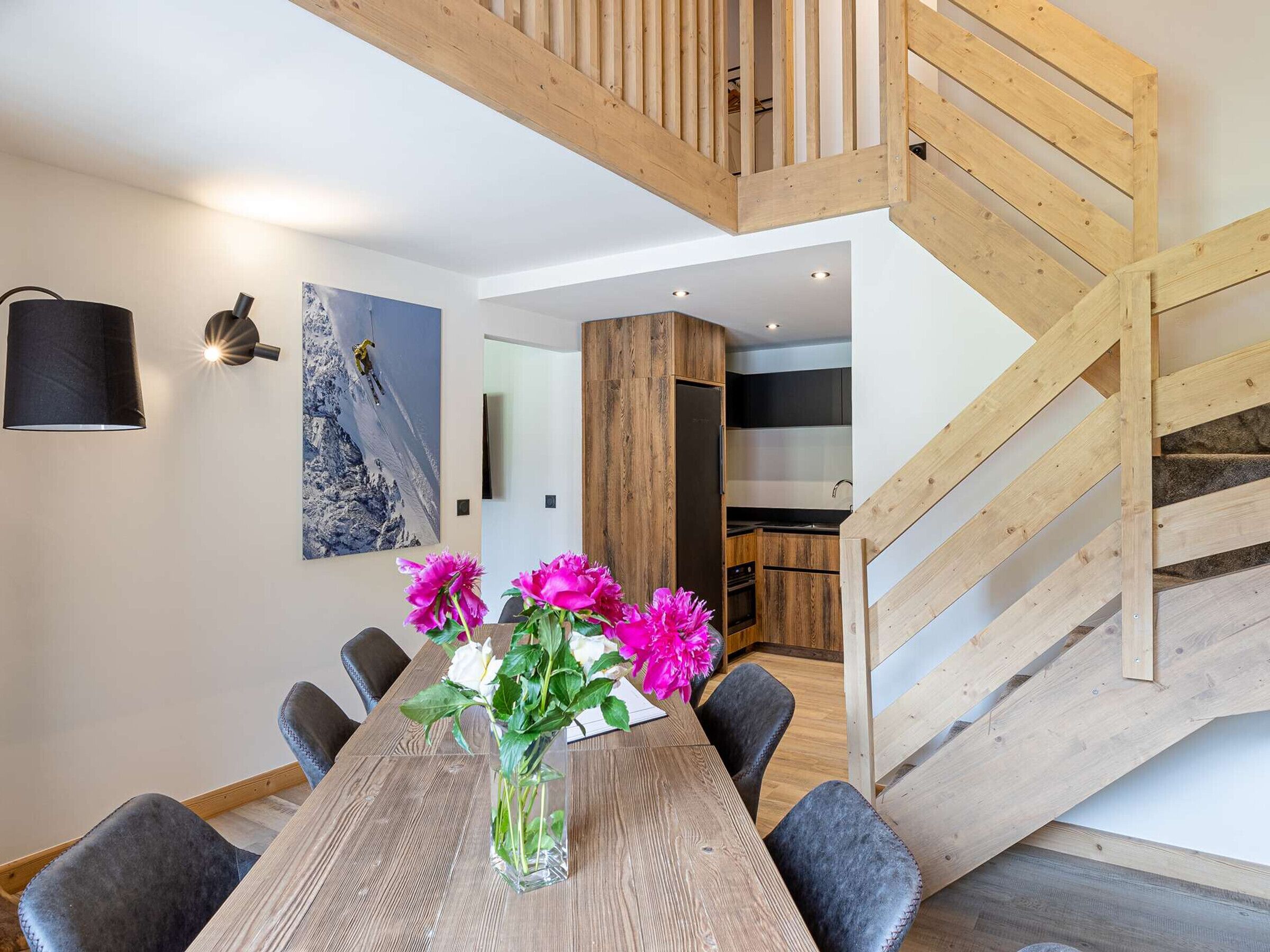 Een modern interieur met een eetgedeelte, een houten trap en een keuken.