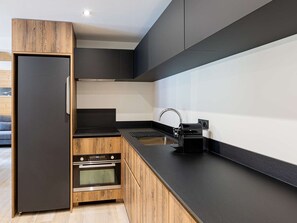 Eine moderne Küche mit Einbauofen, Kaffeemaschine und einem Holzkorpus.