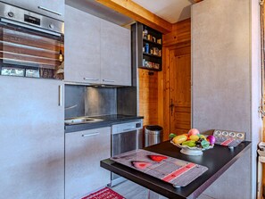 A compact kitchen with a Bosch refrigerator, a dishwasher, a wooden cabinet, and a countertop with a fruit bowl. - Comfortable apartment near slopes - 8 guests (La Plagne)