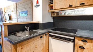 Una cocina con gabinetes de madera, lavavajillas y estufa.