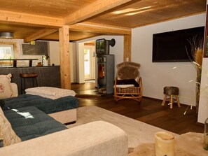 Ein gemütliches Wohnzimmer mit Kamin, einem an der Wand montierten Fernseher und einer bequemen Sitzecke.