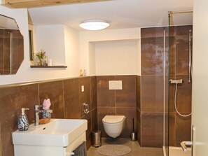 Une salle de bain avec un lavabo blanc, des toilettes et un espace douche.