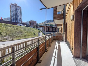 A wooden balcony with a metal railing overlooking a hillside and buildings. - Luxury apartment, prime location - 6 guests (La Plagne)