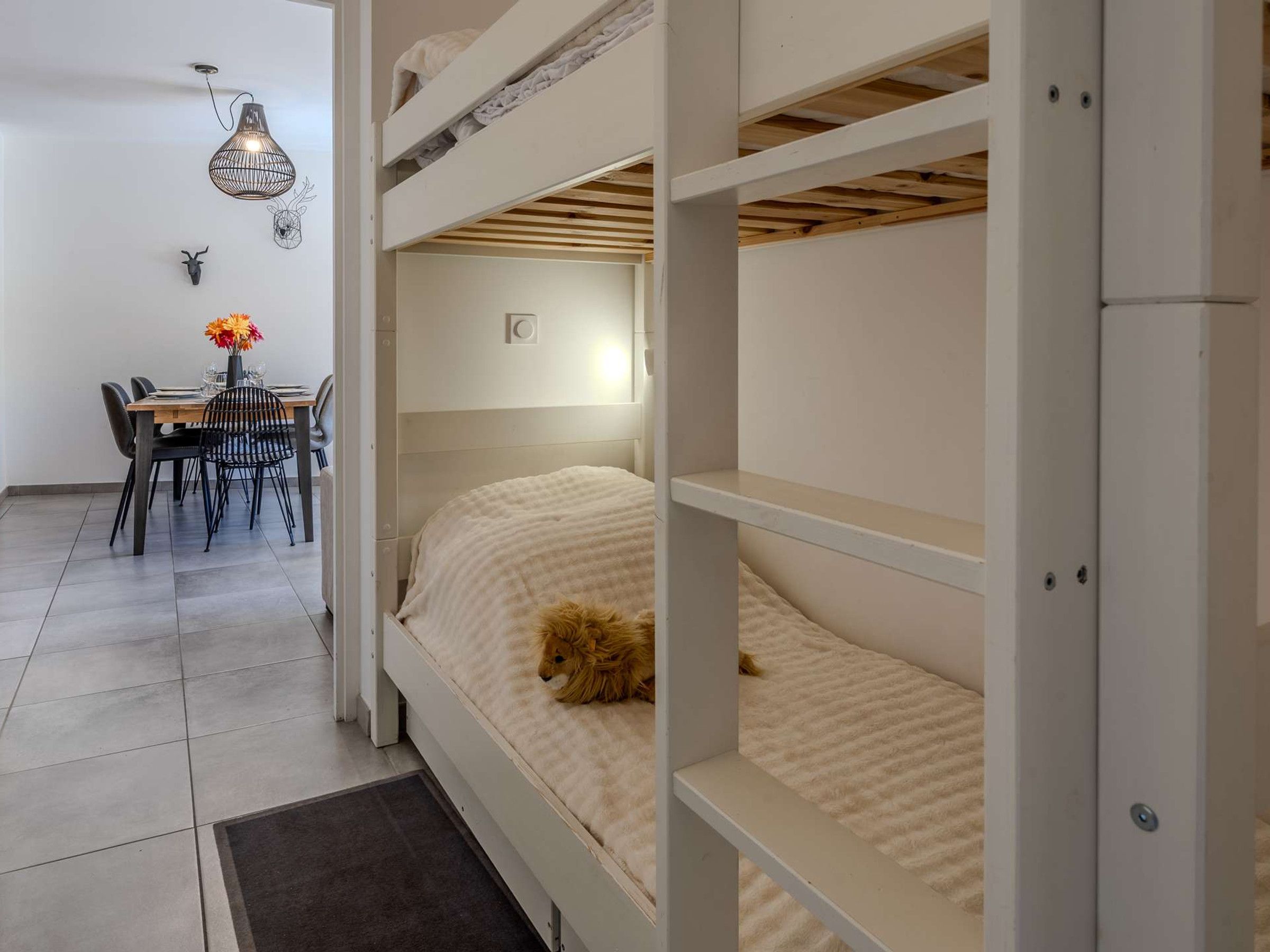 En køjeseng med en hund, et spiseområde med stole og et bord, samt en hængende lampe.