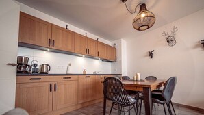 Uma cozinha moderna com armários de madeira, uma mesa de jantar com cadeiras e um lustre.
