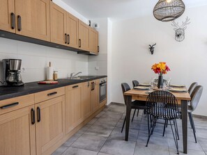 Une cuisine moderne avec des meubles en bois, une machine à café et un coin repas avec une table dressée pour quatre personnes.