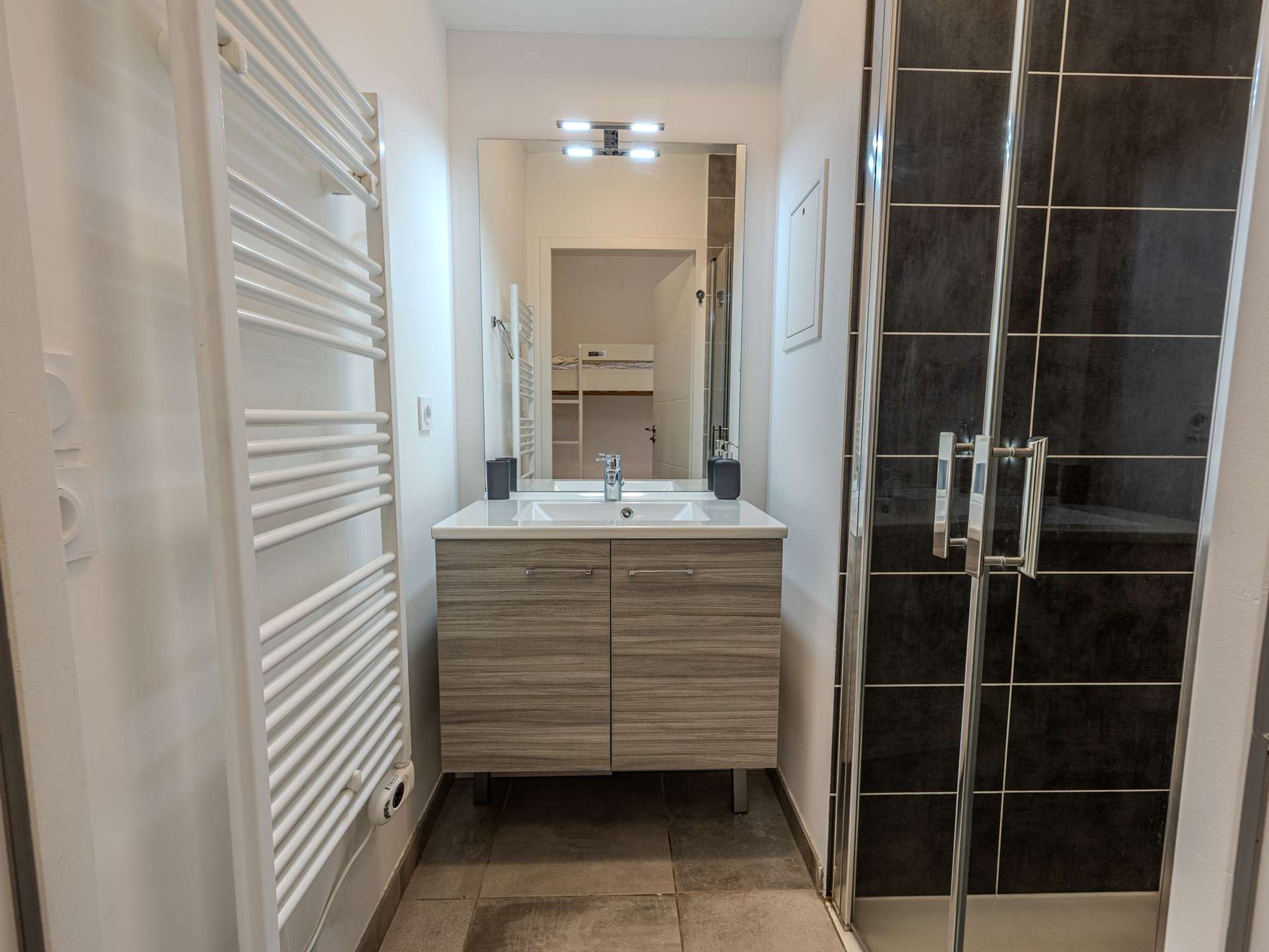Un baño moderno con tocador doble, cabina de ducha de vidrio y ducha a pie.