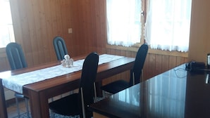 Een eethoek met een houten tafel, zwarte stoelen en een klein wit beeldje.