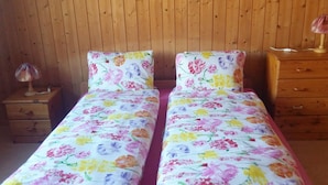 Een tweepersoonsbed met bloemenbeddengoed in een kamer met houten wanden en een nachtkastje met een lamp.