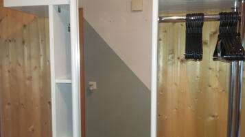 Ein Zimmer mit Holzboden, einer weißen Tür, einem schwarzen Gegenstand auf dem Boden und einer Vorhangstange mit schwarzen Vorhängen.