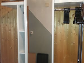 Una habitación con piso de madera, una puerta blanca, un objeto negro en el suelo y una barra para cortinas con cortinas negras.
