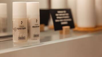 Una estantería con dos botellas etiquetadas como 'hand balm' y 'deodorant', y un letrero negro con texto blanco.