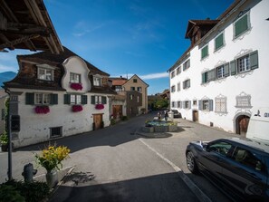 A narrow street with traditional buildings, a fountain, and a parked car.