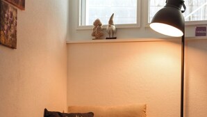 A cozy room with a sofa, a lamp, a small table, and a window with a view.