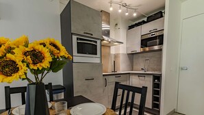 Una cocina moderna con horno integrado, microondas y un comedor con mesa lista para dos.