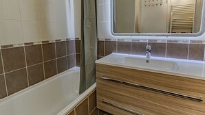 Un baño con bañera, lavamanos, espejo y cortina de ducha.