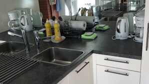 A modern kitchen with a stainless steel sink, white cabinets, and various appliances including a coffee maker and a kettle. - Gäumann-Kiener, (Bad Ragaz), by Interhome (Bad Ragaz)
