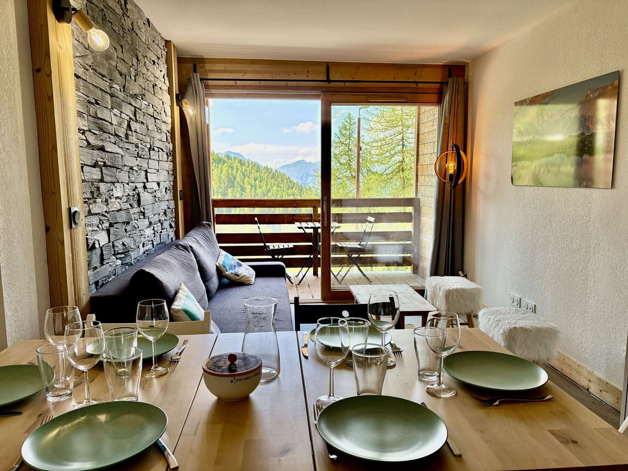 A dining area with a table set for a meal, a sofa, and a view of the outdoors.