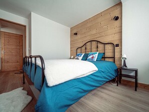 A bedroom with a wooden headboard, a bed with blue bedding, a white throw, and a bedside table with a lamp. - Modern apartment in Plagne Centre - 6 guests (La Plagne)