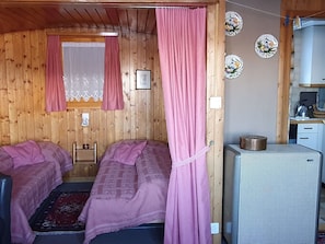 A cabin with two beds, a kitchenette, and a small bathroom.