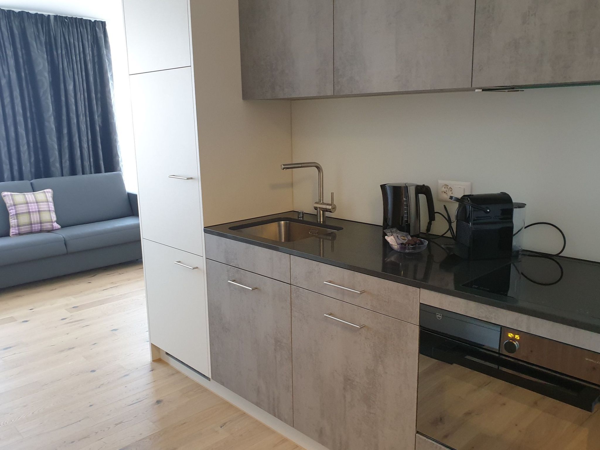 A compact kitchen with a built-in dishwasher, a coffee maker, and a sink.
