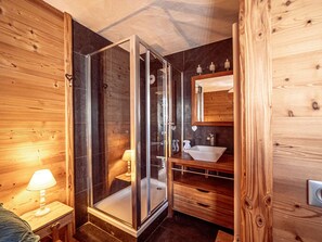 A wooden interior with a glass-enclosed shower, a sink, and a mirror. - Cozy apartment mountain view - 10 guests (Belle Plagne)
