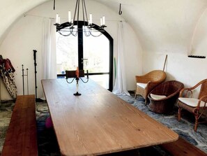 A room with a large wooden table, two wicker chairs, a chandelier, and a window with curtains. - Ferienhaus Heidihuus, (Maienfeld), by Interhome (Maienfeld)