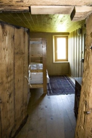 A room with wooden walls, a window, and a bed.